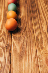 Colored eggs of different sizes on a brown wooden background. Symbol of the Easter holiday. Easter background, front view