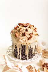 Traditional orthodox Easter cake - Paska with white chocolate and nuts on white round plate on light beige background in rustic style.