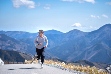 Young Asian man happiness smiling in jacket clothes at the mountain.Funny male running on road in cheerful joyful.Beautiful landscape,Travel Vacation Holiday Concept.