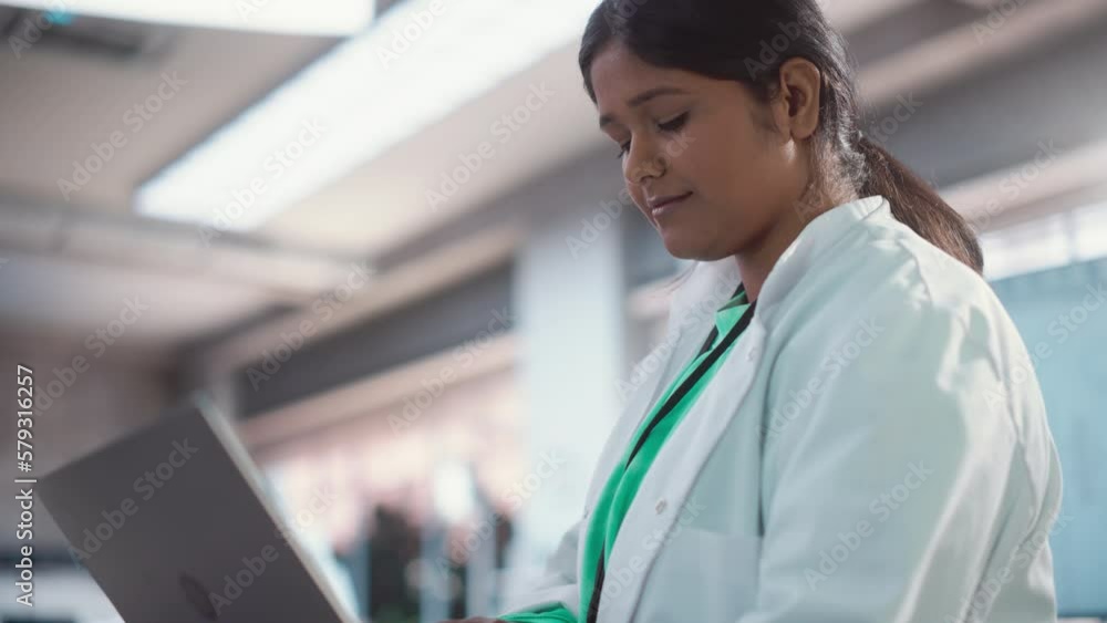 Poster Portrait Close Up of Young Indian Female Specialist in a Lab Coat Smiling and Using Laptop Computer. Professional and Successful Woman Working as an Engineer, Developing High Technology Projects