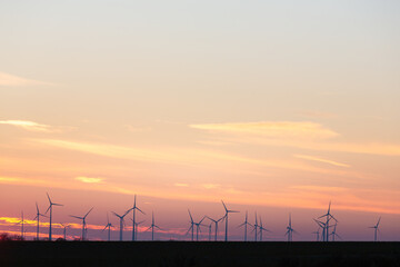 Wind turbines generate energy power electricity during the evening. Sunset, Silhouettes, wind turbines, clean energy
