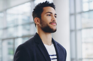 He cant afford to rest on his laurels. Cropped shot of a young businessman showing thumbs up while walking through a modern office.