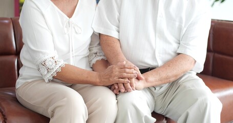 Close up hand of elderly couple holding hands while sitting together at home. Old people holding hands. Focus on hands