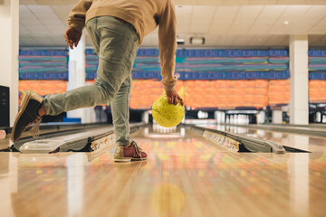 Leisure, sport and entertainment concept, young man throwing yellow ball to alley in bowling - obrazy, fototapety, plakaty