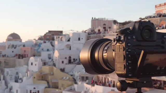 Photography with professional camera, taking pictures of Santorini and traditional white houses at sunset