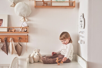 Baby in knitted clothes in children room. Nursery interior