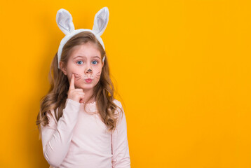 Funny girl with Easter bunny ears on yellow background with copy-space.