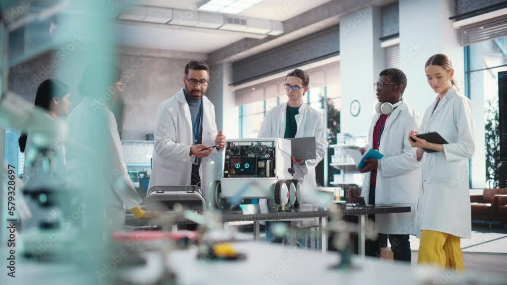 Poster Diverse Team of Industrial Robotics Specialists Gathered Around a Table With a Mobile Robot. Engineers In Lab Coats Discussing an Automated AI Robotic Delivery Assistant, Using Laptop and Tablet