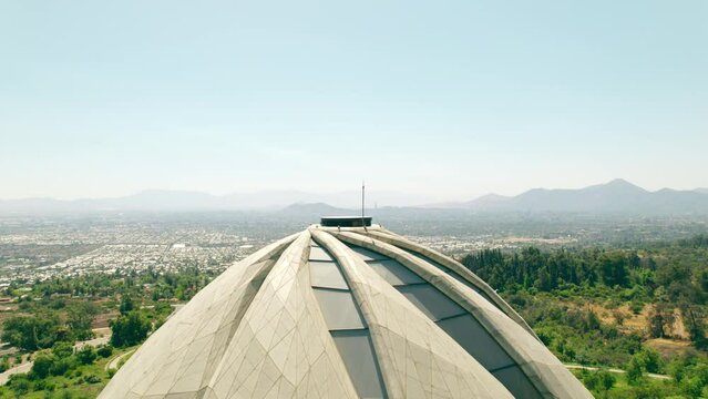Aerial boom up view of the top of the Bahai Temple of South America with the city of Santiago clean, without smog on a sunny day. Parallax effect