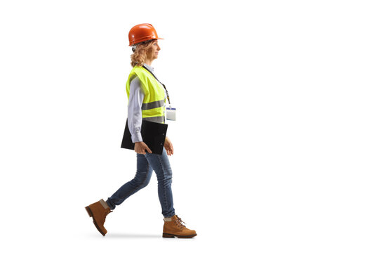 Full length portrait of a female engineer with a safety vest and hardhat walking