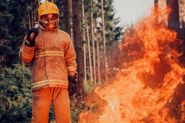 Firefighter at job. Firefighter in dangerous forest areas surrounded by strong fire. Concept of the work of the fire service