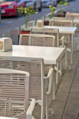 A row of tidy empty white tables in a bar.