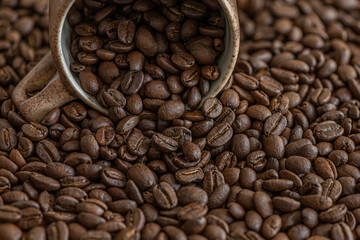 coffee background of roasted coffee beans in a ceramic cup close up, shallow depth of field
