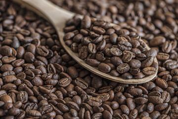 coffee background of roasted coffee beans on a wooden spoon close up, shallow depth of field