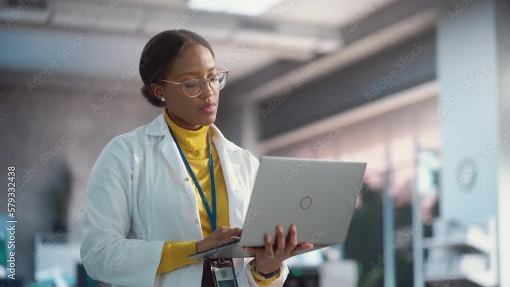 Leinwandbilder portrait of young black female specialist in a lab coat smiling and using laptop computer. professio