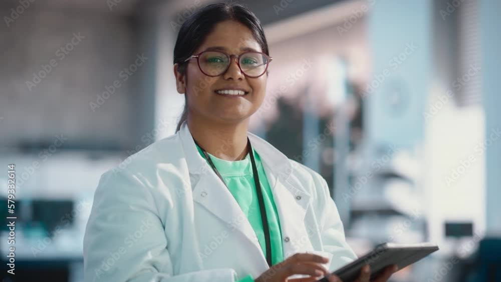 Poster portrait of indian young female scientist using digital tablet computer, looking at camera and smili