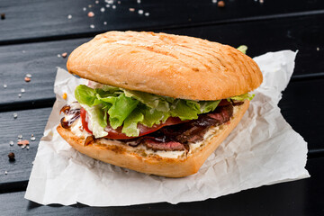 Fast food sandwich with beef, fried onions, lettuce, tomatoes and mayonnaise.