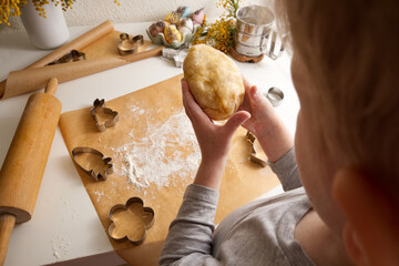 Children's hands carefully hold the dough over the table in spring decor