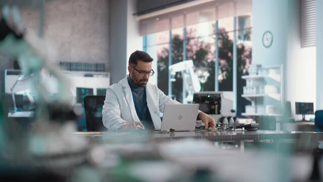 Portrait of a Professional Male Scientist Working in an Industrial Lab Using Laptop Computer. Successful Project Manager Making Strategy Plans for Industrial Production Company, Using Technology