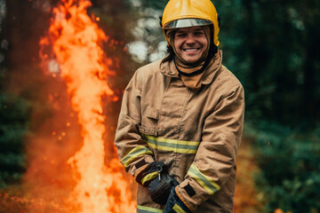 Naklejka premium Firefighter at job. Firefighter in dangerous forest areas surrounded by strong fire. Concept of the work of the fire service
