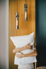 Woman hugging a pillow in a hotel room.