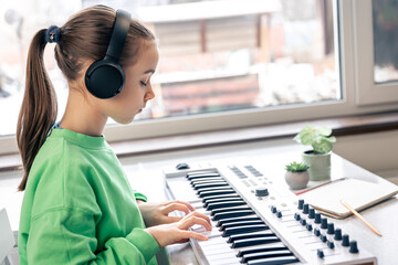 Little girl learning to play the piano at home, music lesson, learning.