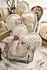 Vintage style handmade lace and linen hearts in wire basket on wooden table