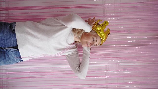 Mature woman with crown golden balloon, fringe party curtain and balloons. Celebrating event