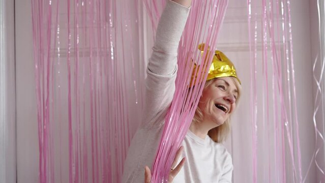 Mature woman with crown golden balloon, fringe party curtain and balloons. Celebrating event