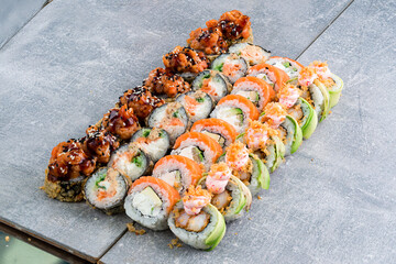 Set of sushi rolls with tuna, salmon, shrimp tempura, cream cheese, avocado, seaweed and sauce with flying fish caviar.