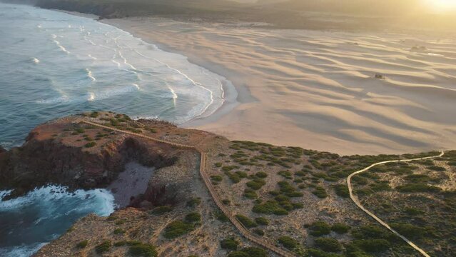 Aerial establishing at sunrise from Praia da Bordeira in the region of Algarve, Portugal. Paradise sand dune beach in front of the Atlantic Ocean.