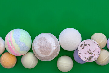 Multicolored bath bombs on a green background, top view.