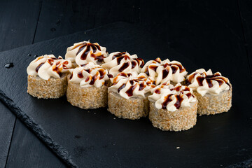 Sushi rolls with salmon, cream cheese, avocado, sesame and teriyaki sauce.