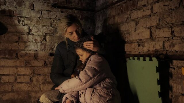 Ukraine war. Shelter. Bunker, Ukrainian mother and child in the basement. With fear suffering and praying peace during war conflict. Refuge.