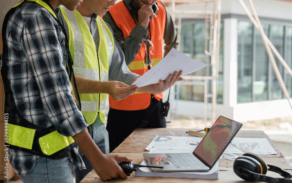 Poster engineer team planning and discussing about construction building on table in working site