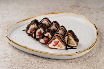 Set of sweet maki sushi rolls with pancake, sweet cream cheese, strawberry, banana and chocolate.