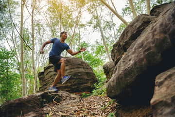 Naklejka na ściany i meble Sport running man in cross country trail run jumping on the rocky mountain path.