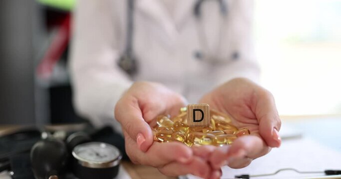 Doctor hands holding a pile of vitamin D capsules with wooden cube with D symbol