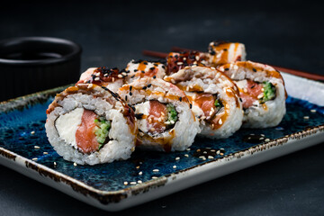 Sushi rolls with salmon, bacon, cream cheese, cucumber, sesame and teriyaki sauce.