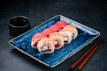 Set of sushi rolls with tuna, shrimps, cream cheese, avocado, flying fish caviar, marinated chuka seaweed and soy sauce.
