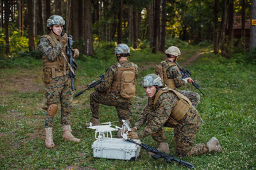 Fototapeta premium Modern Warfare Soldiers Squad are Using Drone for Scouting and Surveillance During Military Operation in the Forest.
