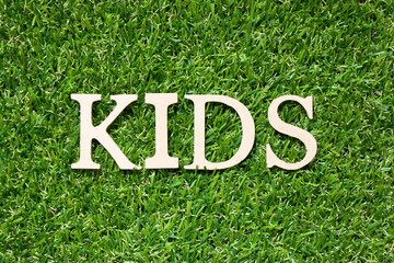 Wood alphabet letter in word kids on artificial green grass background