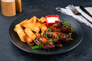 Fried chicken wings with potato chips, green onions and sauce.
