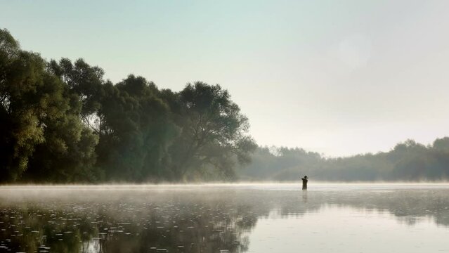 Fisherman catching fish on the current in a foggy summer morning. Fishing on spinning.