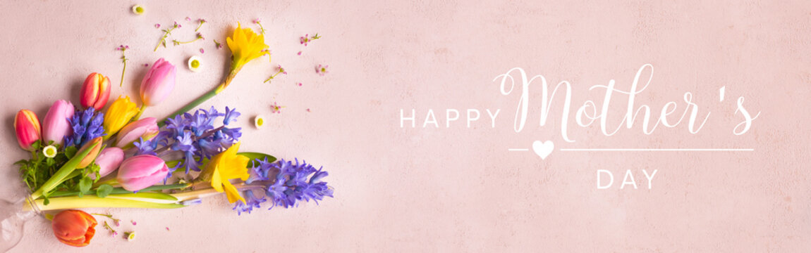 Colorful spring bouquet for mother's day greetings on pastel pink background. Flat lay flower arrangement for greeting cards and banner with english greeting text. 