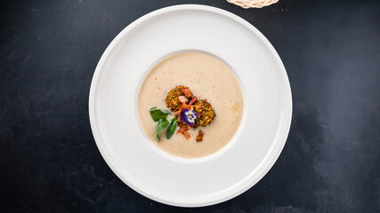 Potato cream soup with bacon, nuts and herbs.