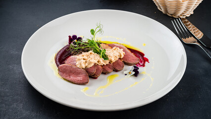 Cold appetizer of duck tagliata with sauce and microgreens.
