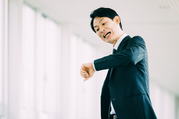 遅刻しそうになって焦る日本人男性ビジネスマン