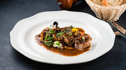 Fried beef cheeks with mushrooms, sauce and herbs.