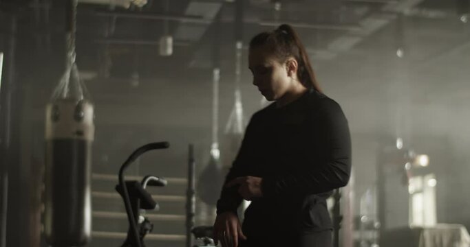 Young female athlete checking pulse on tracker while resting after training